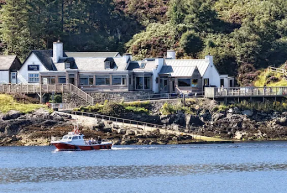 Hotel on the shore of the sea loch with a red boat moored in front