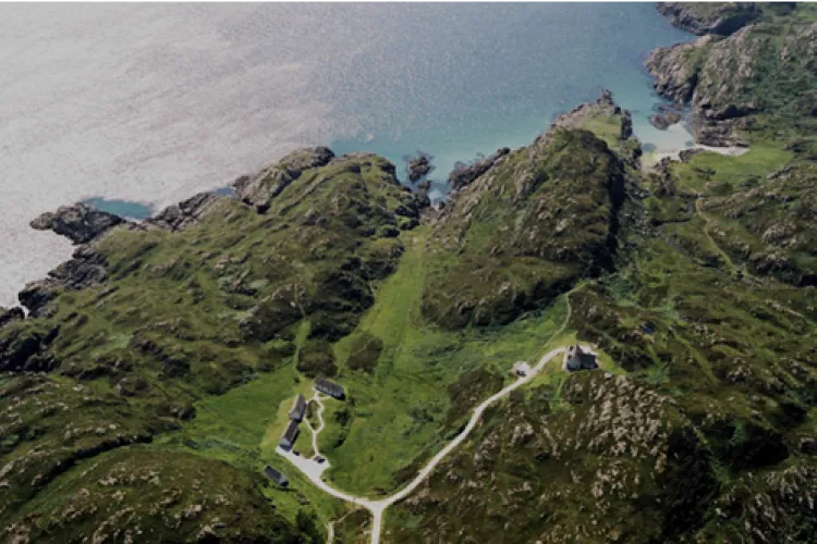 Aerial view of the rocky coast with the track winding down to the cottages and the sea